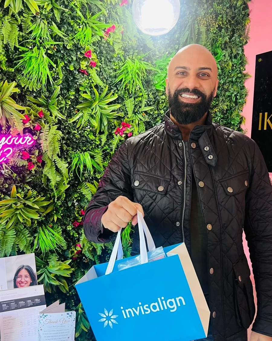 Proud Patient with Clear Aligners at Foliage Wall